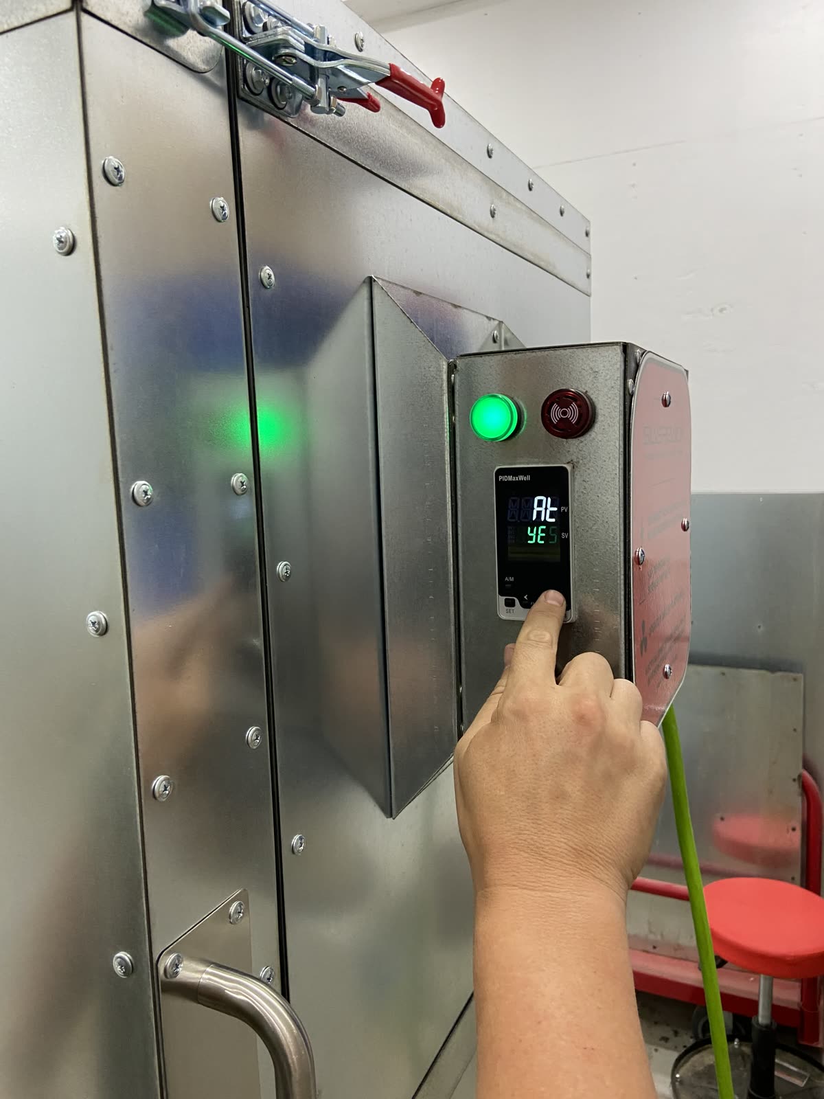 PID controller display showing auto tune engaged while a hand presses the set button